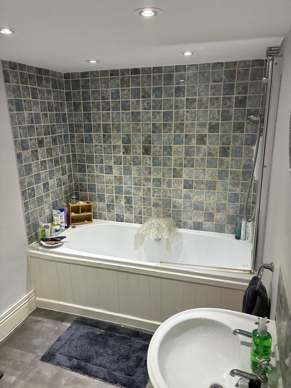 Completed bathroom with grey mosaic tiles and white tub