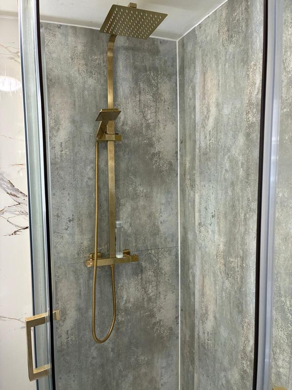 Gold rainfall showerhead with marble-effect tile walls